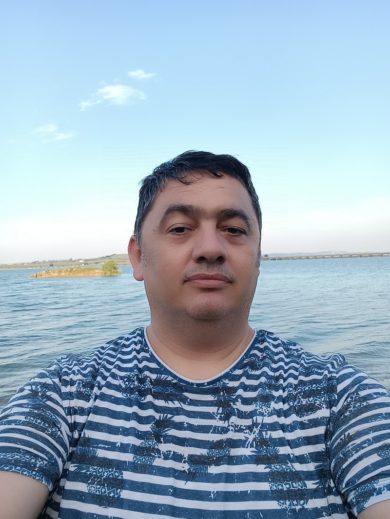 Koray Çokol, arkasında geniş bir göl manzarasıyla açık havada